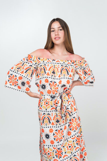 Brineta nosi letnju ANETA haljinu od viskoze i lana u narandžasto-belom dezenu sa spuštenim ramenima.