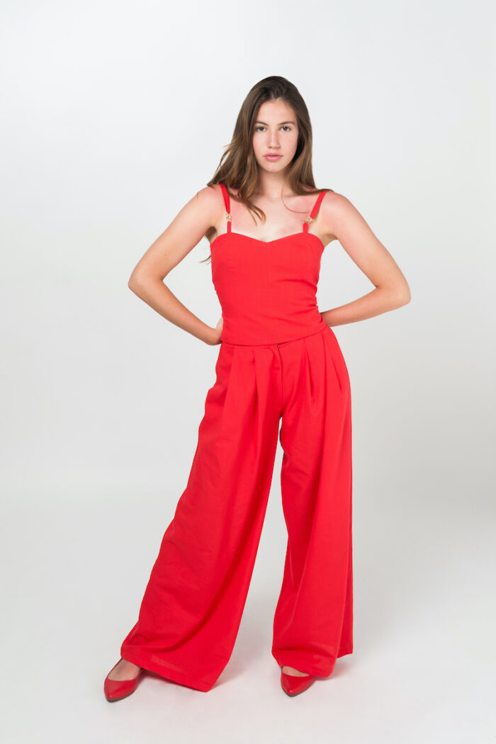 Mlada brineta nosi letnje crvene pantalone širokih nogavica zajedno sa korsetom od istog materijala.