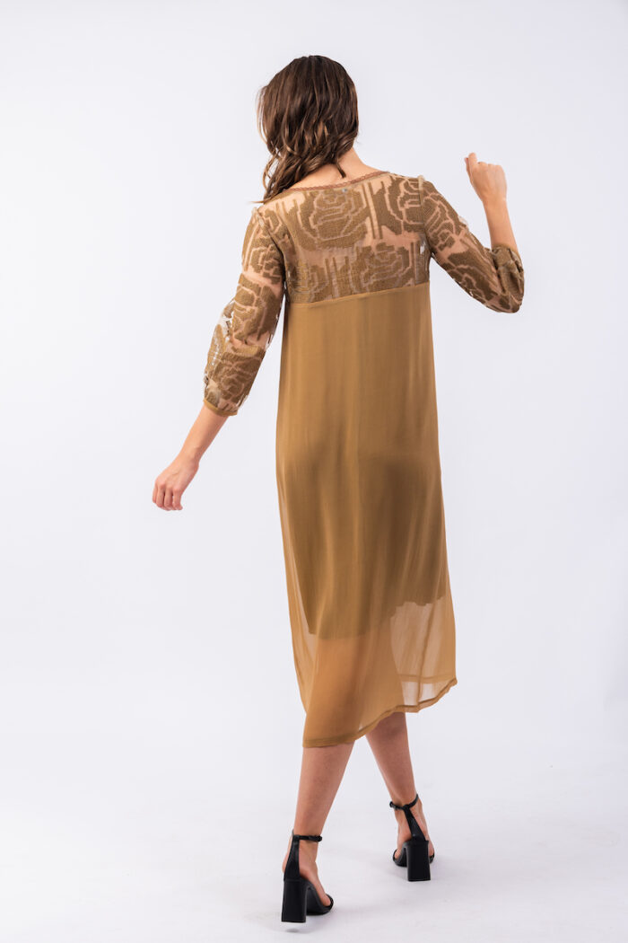 Devojka nosi midi haljinu MILENA od mešavine svile i viskoze sa dezeniranom organdin svilom u gornjem delu haljinue.