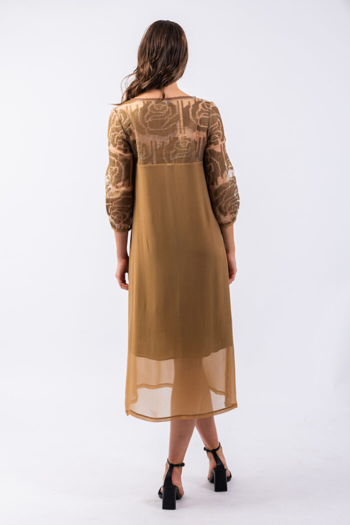 Devojka nosi midi haljinu MILENA od mešavine svile i viskoze sa dezeniranom organdin svilom u gornjem delu haljinue.