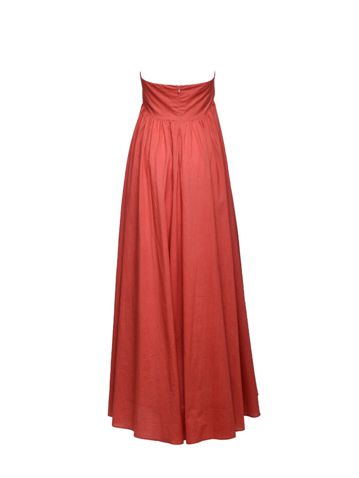 Duga letnja haljina od puplin pamuka u terakota crvenoj boji. Ima štepani korset, gola ramena i dekorativnu traku kao detalj.