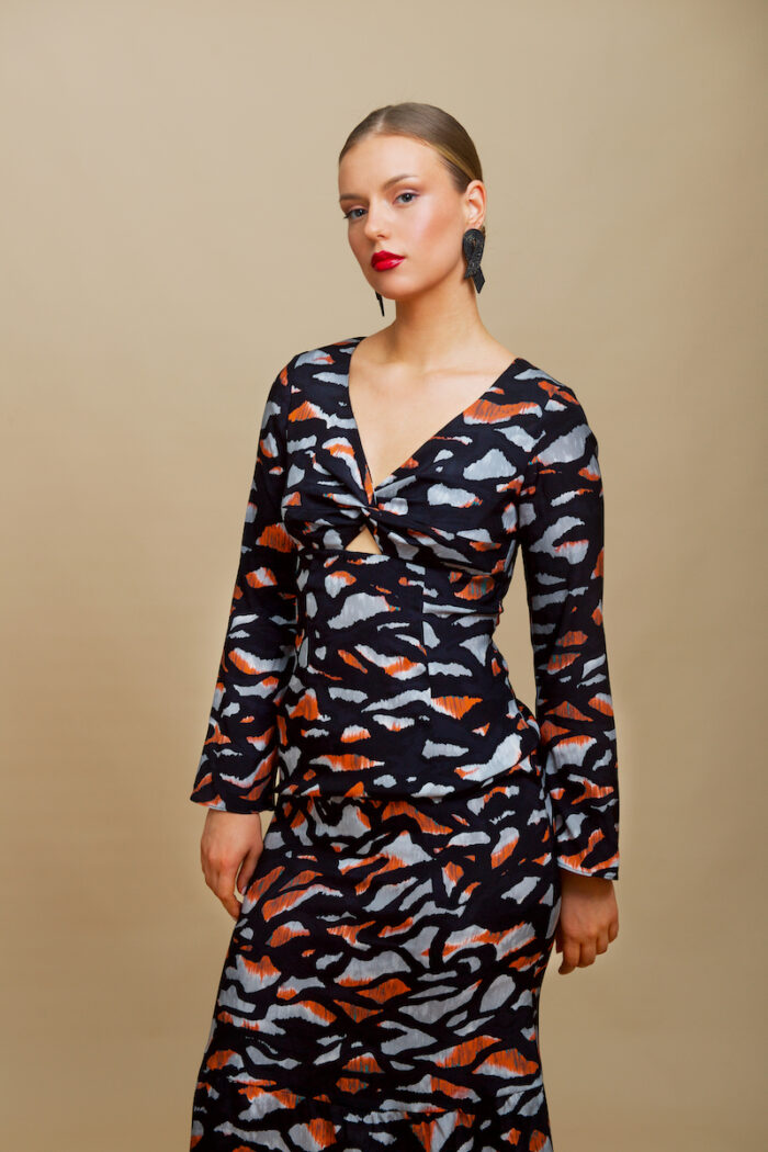 The girl wears a midi EVA dress made of black patterned silk in animal print.