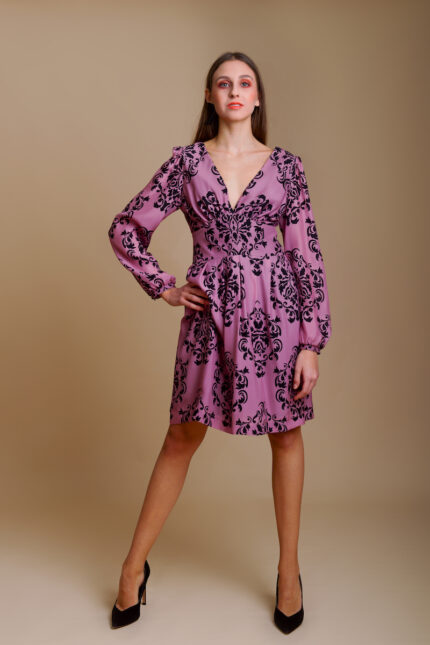 Girl wears short MARIA dress crafted from patterned silk in luxurious shade of purple with black floral details.