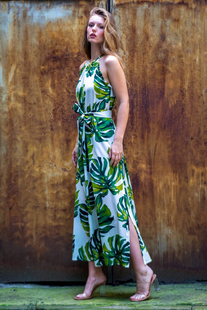The blonde girl wears a long summer dress with a white and green pattern with a plant print.