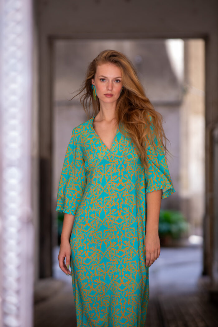 The blonde girl wears a turquoise and yellow SOFIA viscose dress with bell sleeves and a V-neckline.