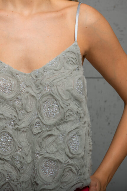 The blonde girl wears a gray top with 3D floral motifs and silver sequins.