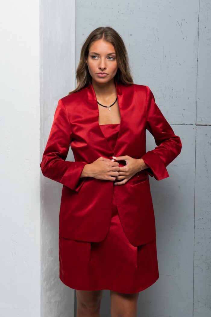 The brunette wears a LIVIA red satin blazer.