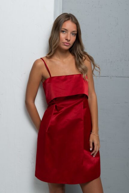 The girl wears a short MADLENA dress made of satin material in dark red.