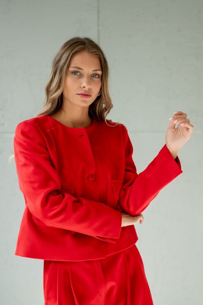 Girl wears short RUBY jacket made from red material with flap pockets.