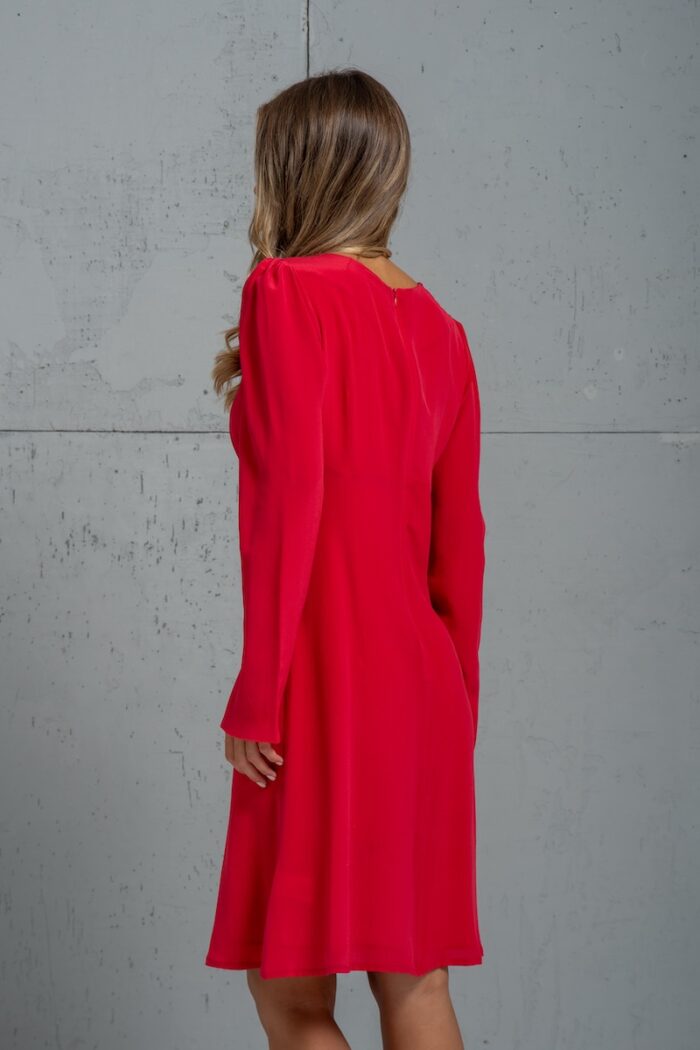 The girl is wearing a short red TEONA silk dress with long sleeves.