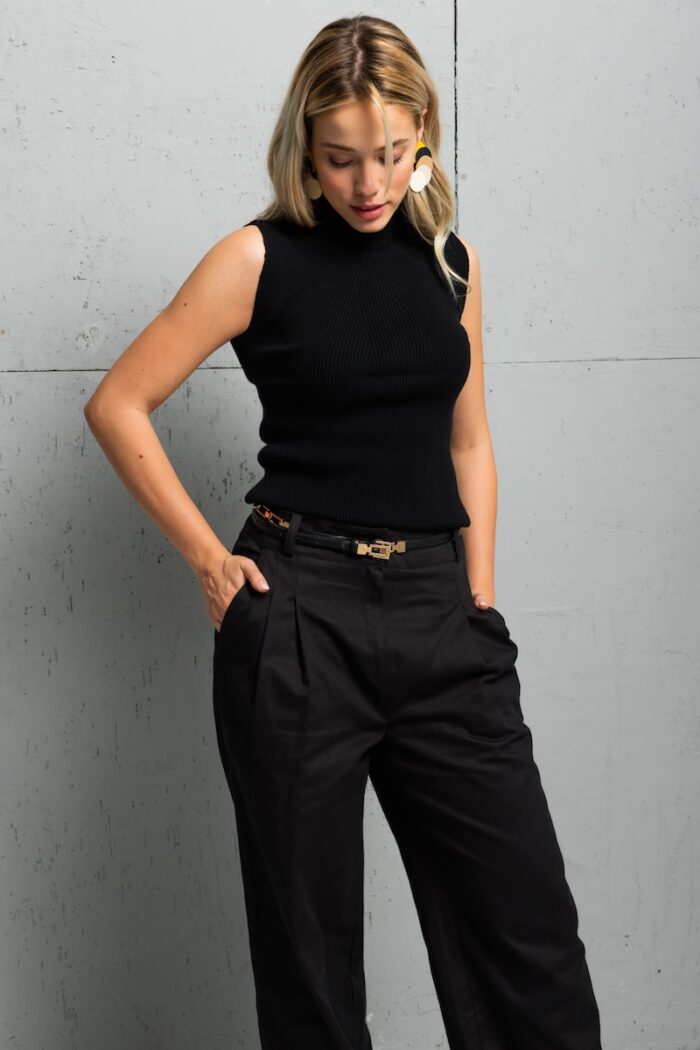 The blonde girl wears a tight black TRIKO sleeveless top with a high neck.