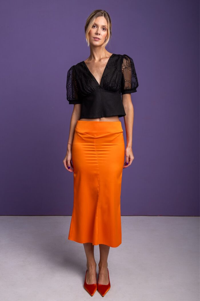 Orange satin skirt photographed in front of a purple background.