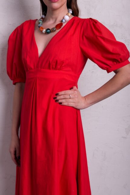 The model is wearing a red midi-length dress with puff sleeves and a V-neckline.