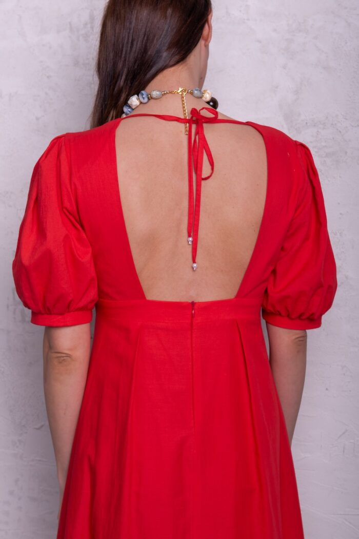 The model is wearing a red midi-length dress with puff sleeves and a V-neckline.