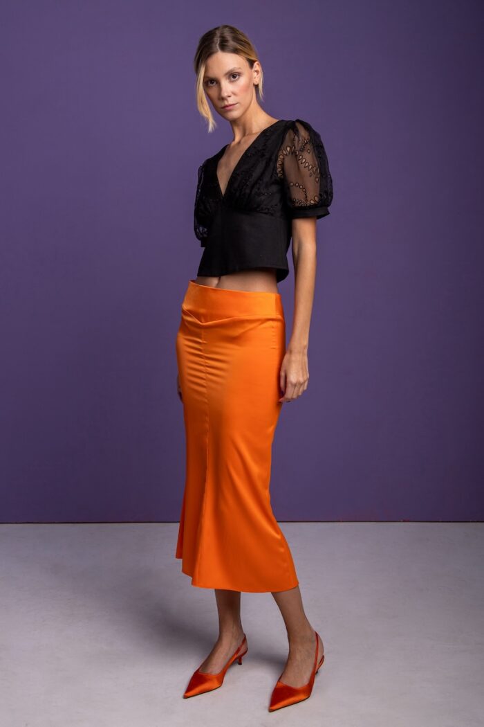 Black V-neck blouse and orange skirt.