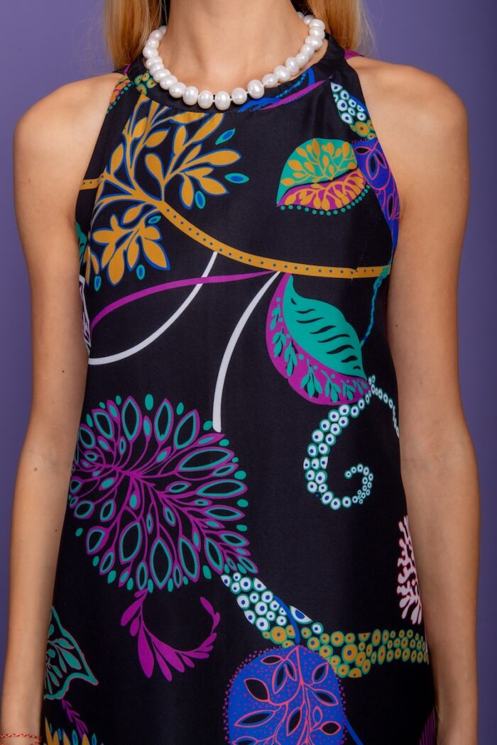 Blonde girl, short black patterned dress, purple-blue background.
