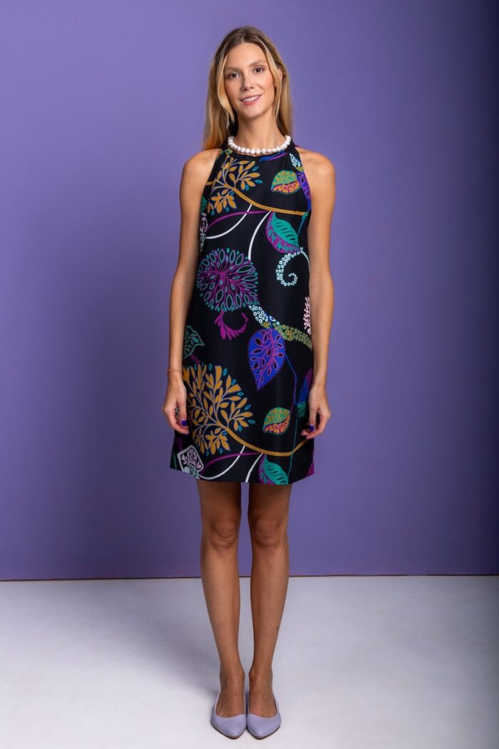 Blonde girl, short black patterned dress, purple background.